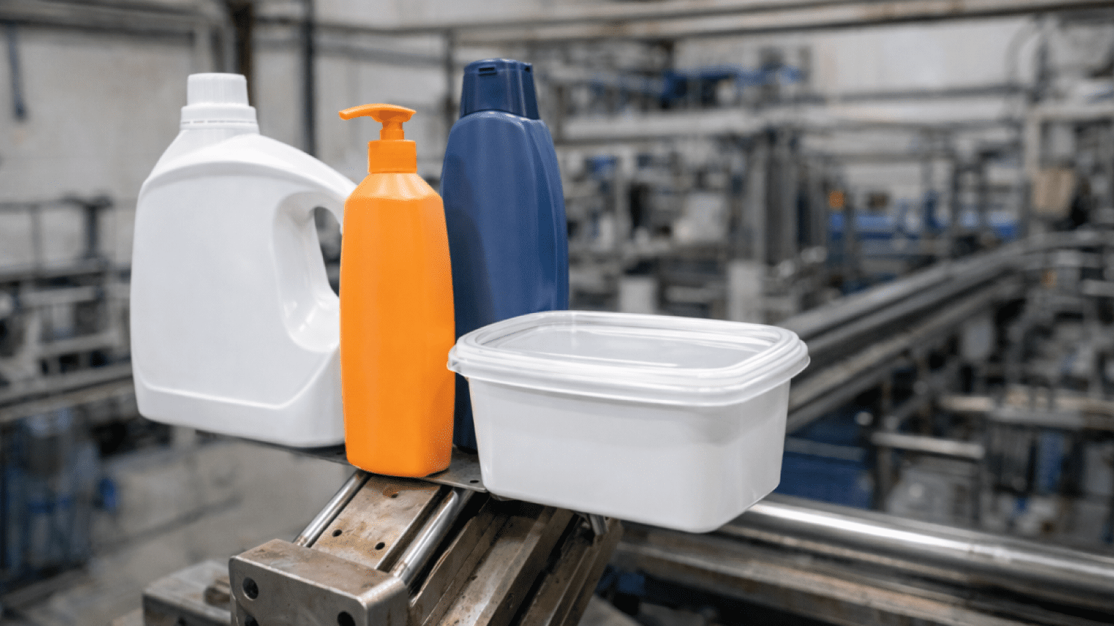 White detergent jug, orange pump bottle, and blue bottle on a conveyor in an industrial setting.