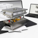 Metal fabrication press stacked with plates on a laptop, CAD models visible on both screens as overlay diagrams