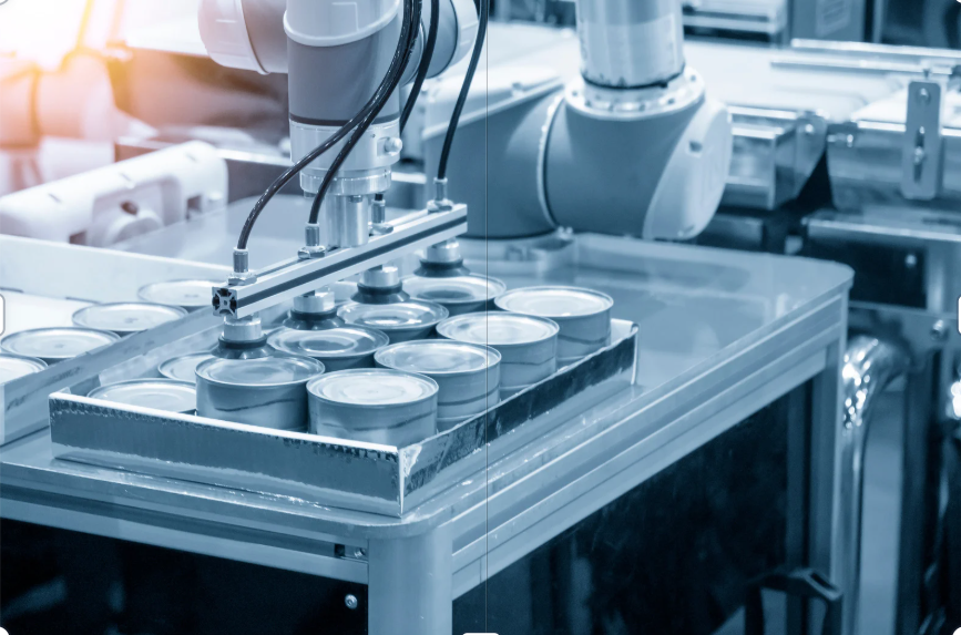 Robotic arm operating on a metal can production line, handling cans on a conveyor.